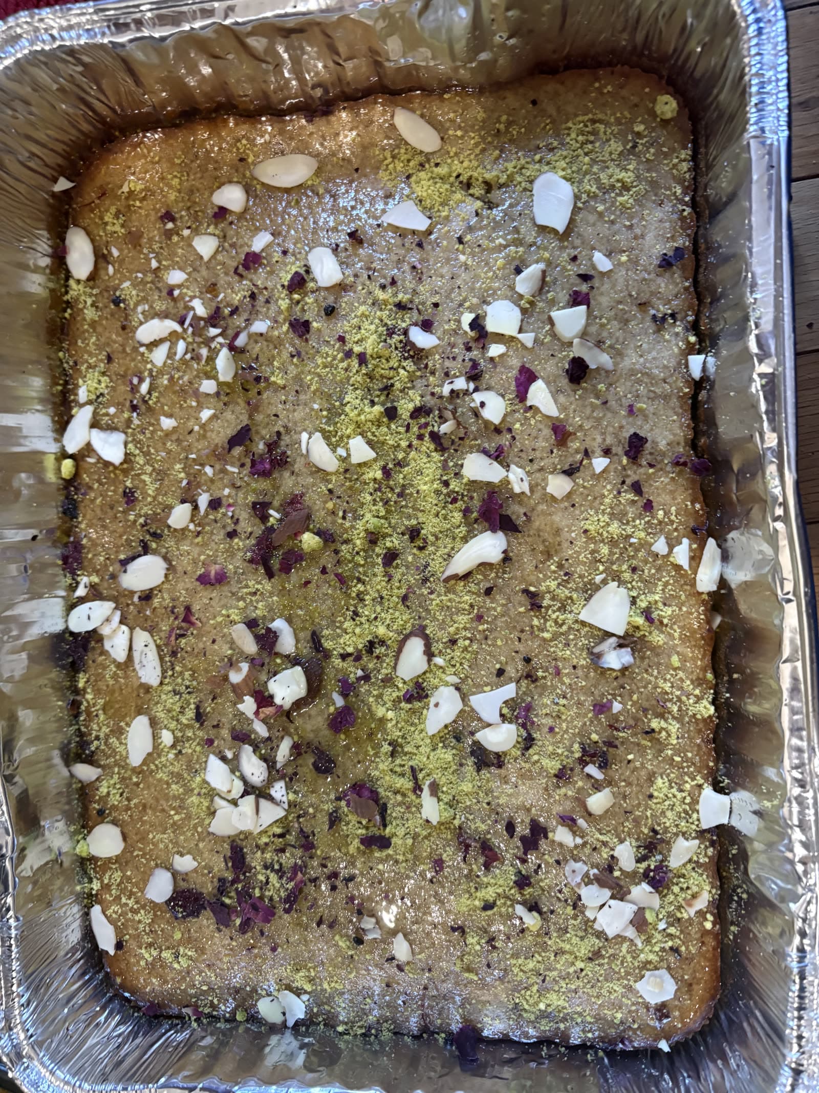 Syrup-soaked gulab jamun cake with pistachios, almonds, and rose petals.
