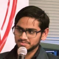Portrait of Tanay Mangal speaking at a microphone
